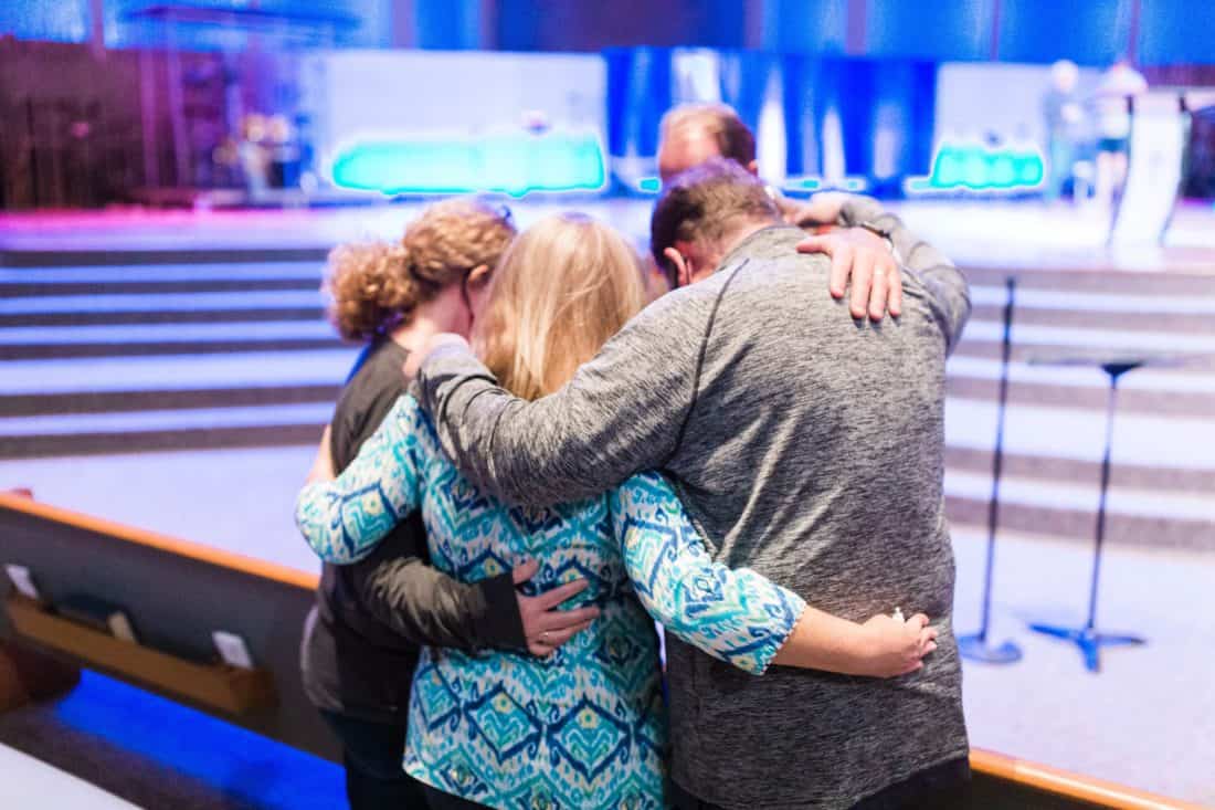 Four people praying together at church.